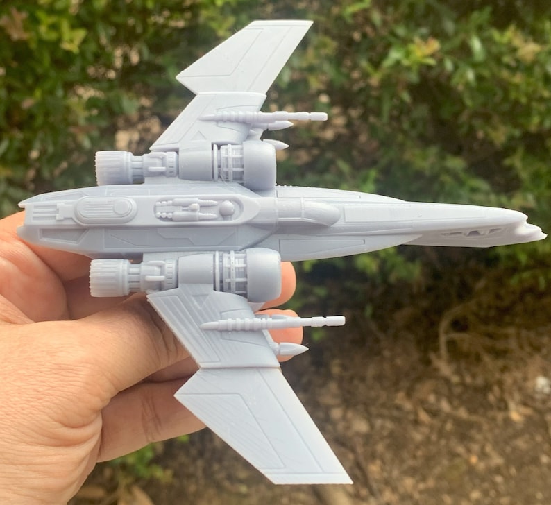 Pode incluir: Um modelo de nave espacial de pl&aacute;stico cinza com duas asas e v&aacute;rios motores. O modelo &eacute; detalhado com partes do motor e armas vis&iacute;veis.