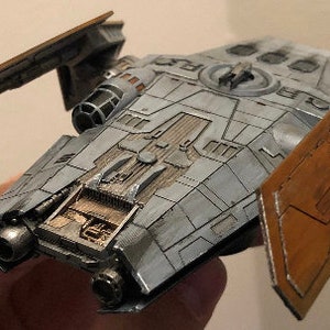 Peut inclure: Un mod&egrave;le d&eacute;taill&eacute; d'un vaisseau spatial avec un sch&eacute;ma de couleurs gris et brun. Le vaisseau spatial a un dessus plat et large avec un petit cockpit rond &agrave; l'avant. Le vaisseau spatial a deux ailes qui sont repli&eacute;es. Le mod&egrave;le est en plastique et mesure environ 25 cm de long.