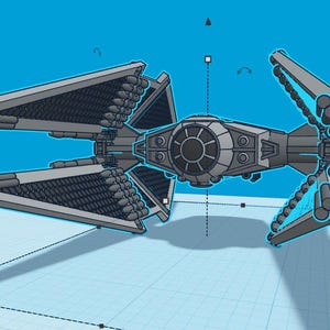 May include: A gray TIE fighter spaceship with a black cockpit and multiple cannons on the wings. The spaceship is on a blue background with a grid pattern.