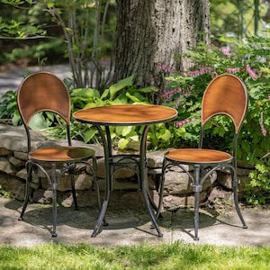 May include: A small, round, brown wooden table with a black metal frame and two matching chairs. The chairs have brown wooden seats and backs with black metal frames. The table and chairs are set on a stone patio with green grass in the background.