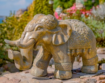 May include: A gold-colored elephant statue with intricate details and a patterned design on its back. The statue is standing on a stone surface.