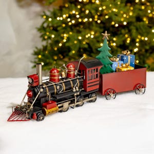 Peut inclure: Un train de Noël décoratif avec une locomotive noire et un wagon rouge. Le wagon est rempli d'un sapin vert et de cadeaux emballés. L'arrière-plan présente des lumières de Noël floues.