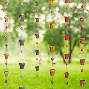 May include: A metal rain chain with multiple small, colorful pots hanging from it. The pots are in various shades of red, yellow, blue, and green. The chain is made of metal links and has a rustic, vintage look.