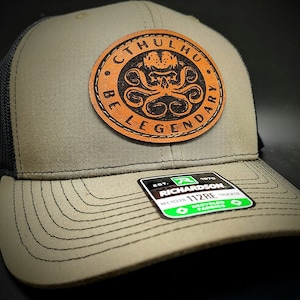 May include: A green and black trucker hat with a brown leather patch that says "Cthulhu Be Legendary" with a black and white image of a tentacled creature. The hat is made by Richardson 112RE.