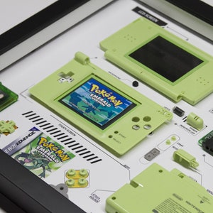 May include: A disassembled green Game Boy Advance SP with a Pokemon Emerald game cartridge. The parts are laid out on a white surface with diagrams and labels.