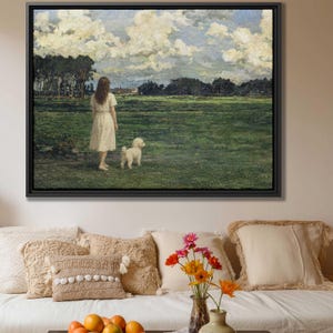Puede incluir: Un cuadro de paisaje enmarcado que representa a una persona con un vestido de color claro de pie en un vasto campo verde con un pequeño perro blanco. La escena incluye árboles de color verde oscuro a lo lejos bajo un cielo lleno de nubes blancas.