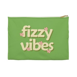 May include: A green zippered pouch with the text "fizzy vibes" in a light yellow font with pink flower accents.