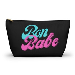 May include: Black canvas zippered pouch with the text "Bon Babe" in pink and blue retro lettering.
