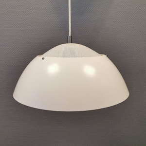 Op de afbeelding: Een witte hanglamp met een witte metalen kap en een wit snoer dat aan het plafond hangt.