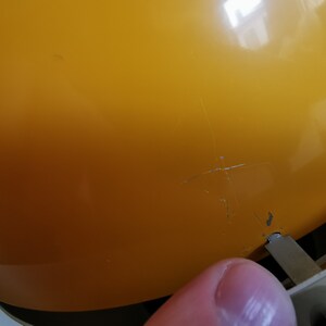 May include: A yellow plastic lampshade with a crack in the surface.