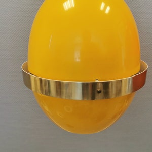 May include: Two hanging pendant lights with yellow and orange egg-shaped shades and gold metal rims.