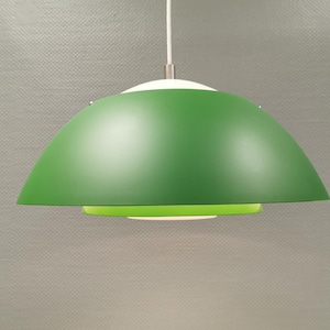 Op de afbeelding: Een moderne hanglamp met een groene, koepelvormige kap. De lamp heeft een wit bovenstuk en een felgroen onderstuk, met een wit ophangsnoer. Het ontwerp is minimalistisch en geschikt voor diverse interieurstijlen.