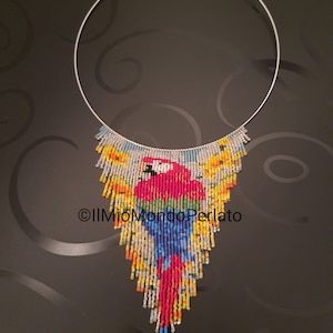 Puede incluir: Un collar de cuentas de colores con un diseño de loro cuelga de un choker de alambre plateado. Las cuentas están dispuestas en cascada, creando una pieza de joyería vibrante y llamativa.