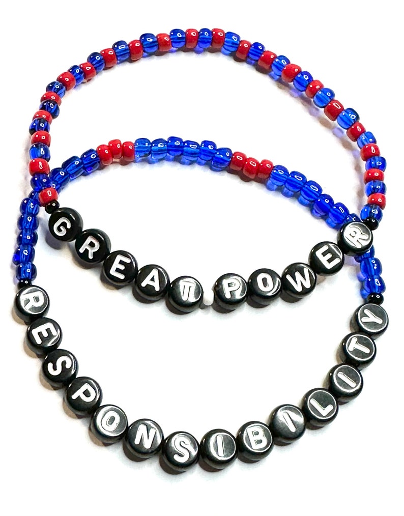 May include: Two beaded bracelets with the words "Great Power" and "Responsibility" spelled out in black beads with white lettering. The bracelets are made with blue and red beads.
