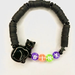 May include: Black and white cat charm bracelet with black rubber beads and colorful letter beads spelling "BINX".