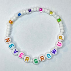 May include: White beaded bracelet with the words "NEVER GROW UP" spelled out in colorful letters.