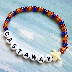 May include: A white beaded bracelet with the word "CASTAWAY" spelled out in black letters. The bracelet is made with orange, yellow, and blue beads and has a white starfish charm.