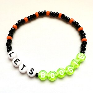 May include: A black and orange beaded bracelet with the words "Let's Boogie" spelled out in white letters on green beads.