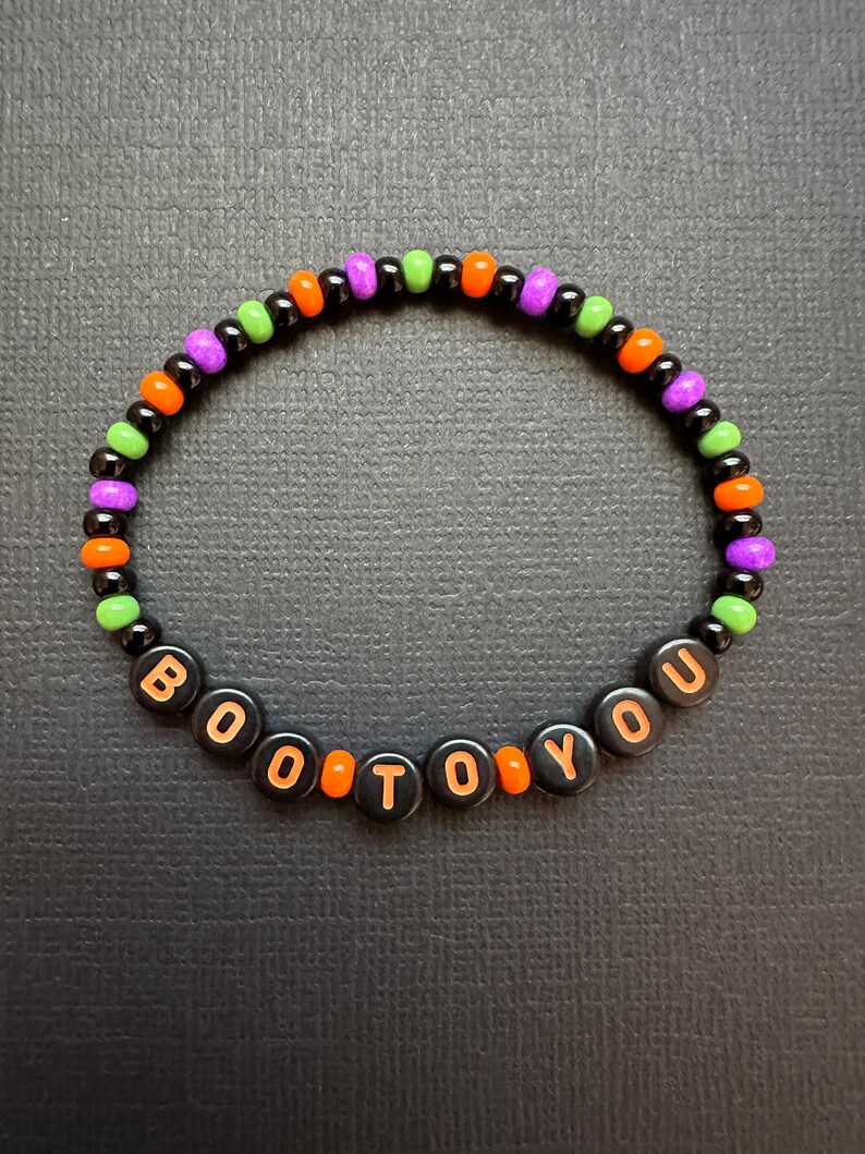 May include: A black beaded bracelet with orange, green, and purple beads spelling out "BOO TO YOU".