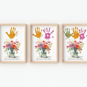 May include: Three framed prints with handprints in yellow, green, and pink, with the text "Aller Gute zum Geburtstag" at the bottom of each print. Each print features a watercolor bouquet of flowers in a glass jar.