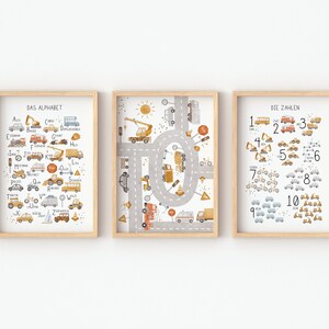 May include: Three framed prints with a light wood frame. The prints feature a colorful illustration of vehicles and transportation. The first print shows the alphabet with each letter paired with a vehicle. The second print shows a circular road with various vehicles. The third print shows numbers 1-10 with each number paired with a vehicle.