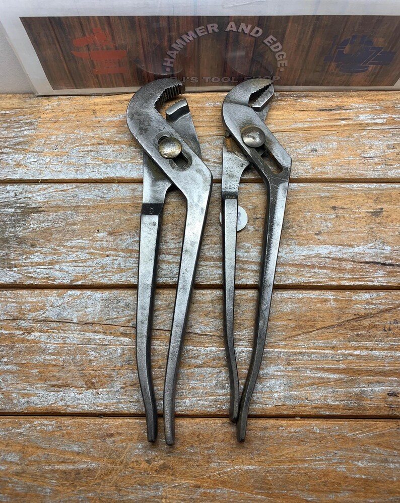 K&ouml;nnte beinhalten: Zwei alte Wasserpumpenzangen mit silbernem Finish, angeordnet auf einer Holzoberfl&auml;che. Die Zangen haben verstellbare Backen und lange Griffe. Oben im Bild befindet sich ein Schild mit der Aufschrift "HAMMER AND EDGE".