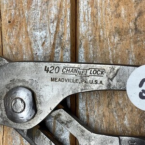 K&ouml;nnte beinhalten: Nahaufnahme einer silberfarbenen Channel Lock 420 Zange. Der Text "CHANNEL LOCK" und "MEADVILLE, PA. U.S.A." sind sichtbar. Ein wei&szlig;er Aufkleber mit der Nummer "83" ist an der Zange angebracht.