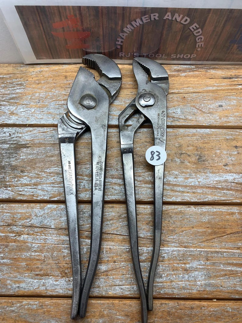 K&ouml;nnte beinhalten: Zwei silberfarbene Kanalzangen aus Metall mit strukturierten Griffen und verstellbaren Backen. Auf den Zangen steht "420 CHANNEL LOCK" und "CHAMPION DE ARMENT". Ein Preisschild mit der Nummer "83" ist an einer der Zangen befestigt. Der Hintergrund enth&auml;lt den Text "HAMMER AND EDGE" und "RJ'S TOOL SHOP".