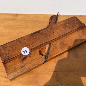 May include: A vintage wooden hand plane with a metal blade. The plane is a warm brown color and shows signs of wear. A white sticker with the number 29 is affixed to the wood. The tool is designed for woodworking and carpentry.