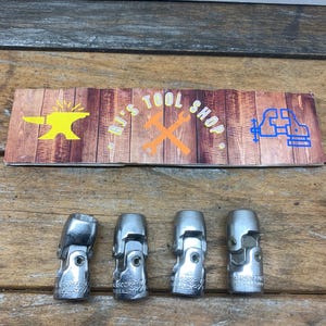 May include: Four silver universal joint sockets with the text "H.K.S. CORP. 7/16" and "ALL ALLOY" printed on them.