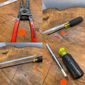 May include: A collection of tools including a wire stripper with red handles, a screwdriver with a yellow handle, a metal ruler, and a multi-bit screwdriver. The tools are arranged on a wooden surface.