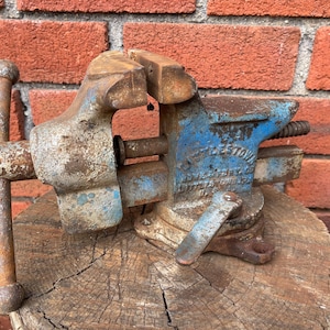 May include: A vintage blue metal bench vise with heavy rust and wear. The side of the tool features embossed text reading Littlestown Hardware & Foundry Co. Littlestown PA U.S.A. It includes a T-shaped handle and a swivel base locking lever.