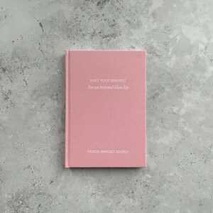 May include: A pink journal with the text "Shift Your Mindset For an Internal Glow Up" and "Fitness. Mindset. Energy" on the front cover.