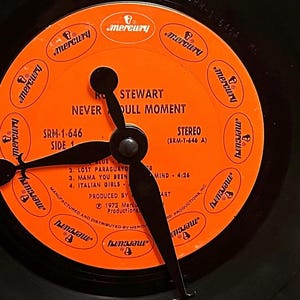 May include: An orange vinyl record with the text "Rod Stewart Never a Dull Moment" and "SRM-1-646 Side 1" printed on it. The record label has a Mercury logo and the text "Stereo (SRM-1-646 A)".