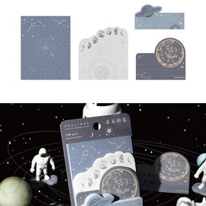 May include: A set of 100 celestial-themed sticky notes in a blue and white colour scheme. The notes feature a variety of designs, including stars, planets, and moons. The packaging includes the text "cardlover paper memo" and "星辰傾落".