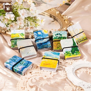 May include: A set of nine small, colourful notebooks with elastic bands. Each notebook features a different famous painting, including Starry Night and Wheatfield with Crows.