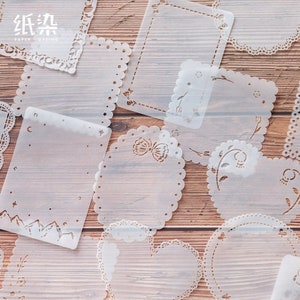 May include: A set of 10 white paper stencils with various designs, including floral, butterfly, and geometric patterns. The stencils are on a wooden background.  The text "纸染" is visible in the top left corner of the image.
