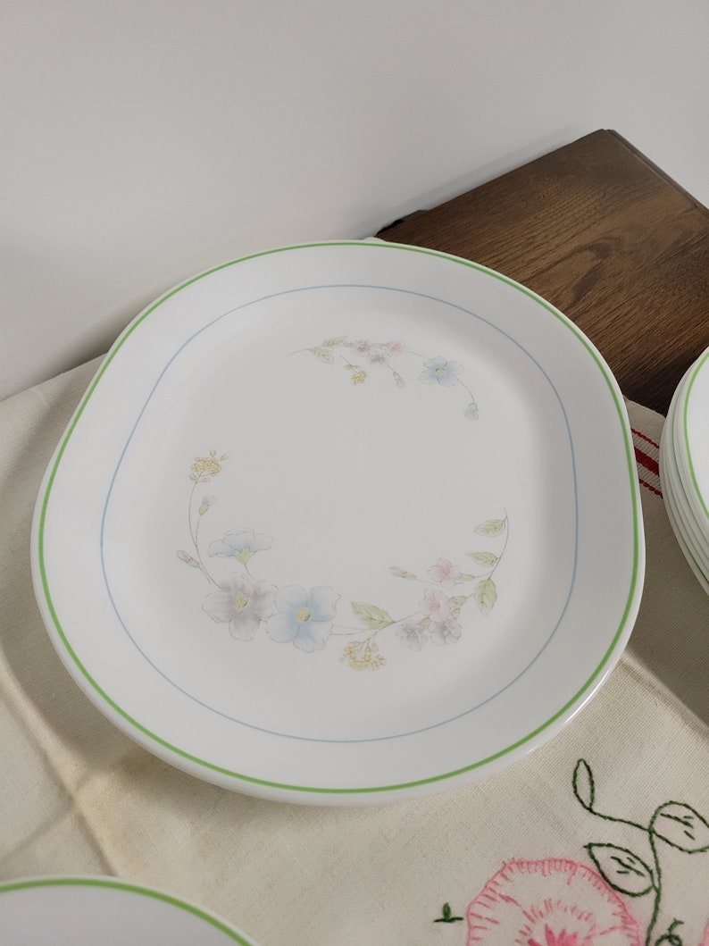 May include: A white oval serving platter with a green rim and a floral design in shades of blue, pink, and yellow.