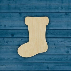 May include: A wooden Christmas stocking cutout, unpainted, with a rounded toe and a folded top. The stocking is on a blue woodgrain background.