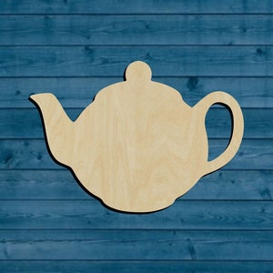 May include: A wooden cutout of a teapot, a classic kitchen item, in a light brown color. The teapot is on a blue wooden background.