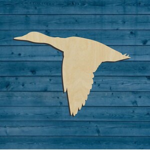 May include: A wooden cutout of a goose in flight. The goose is light brown and is against a blue wood background.
