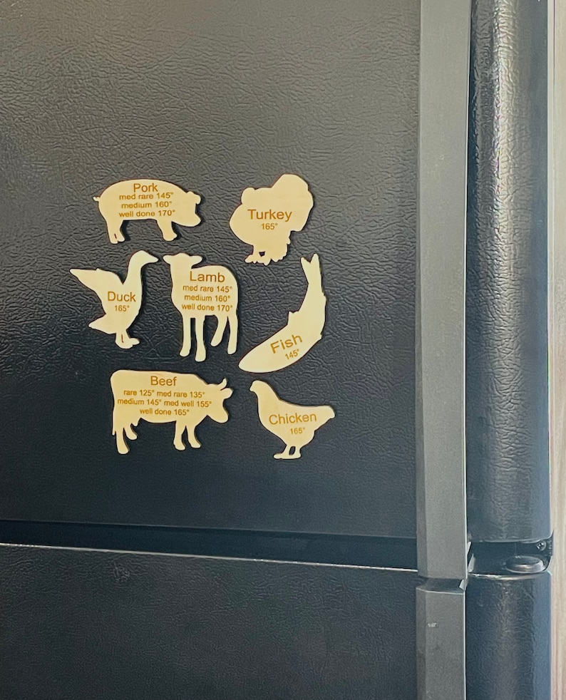May include: A set of wooden refrigerator magnets shaped like different animals, each with a name and internal temperature guidelines for cooking. The animals include a pig, turkey, duck, lamb, fish, cow, and chicken.