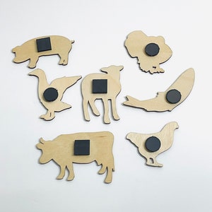 May include: Set of 8 wooden animal magnets with black magnetic backing. The animals include a pig, goose, cow, chicken, lamb, fish, and turkey.