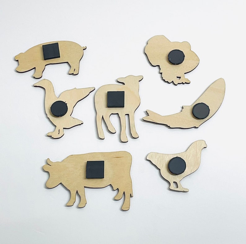 May include: Set of 8 wooden animal magnets with black magnetic backing. The animals include a pig, goose, cow, chicken, lamb, fish, and turkey.