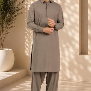 May include: A taupe-colored long-sleeved kurta shirt with a classic collar and a buttoned placket, paired with matching loose-fitting trousers. The ensemble features a solid, neutral tone and a clean, structured design with cuffed sleeves.