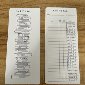 May include: Two white rectangular cards. One card has a stack of books with the words "Book Tracker" above. The other card is a reading log with spaces for title, dates, and ratings. The words "Reading Log" are at the top.