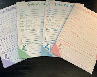 May include: Four colorful book review notepads. Each notepad features a title, author, genre, and rating sections. The pads have a torn paper edge design with hearts and stars. The text "Book Review" is at the top of each pad.