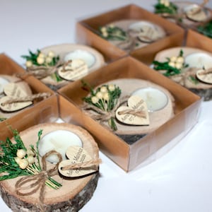 May include: A set of small wooden candle holders with a heart-shaped tag that says "Anna & Martin 07.11.2020". Each holder has a small white tea light candle and a sprig of greenery with white berries.