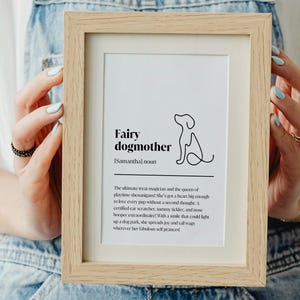 May include: A framed print with a white background and black text that reads "Fairy dogmother [Samantha] noun". The text defines a fairy dogmother as the ultimate treat magician and the queen of playtime shenanigans. The print features a simple line drawing of a dog.