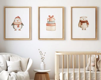 May include: Three framed watercolor prints featuring a penguin in a hat and scarf, a stack of gifts with a bow, and an owl wearing a scarf. The prints are in wooden frames, perfect for a nursery or children's room.